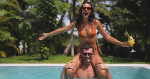 Couple Having Fun In A Tropical Pool With Playful Summer Vibes