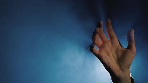 Hand Reaching in Light Against Smoky Blue Background