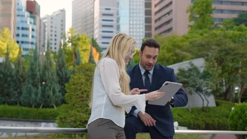 Dos jóvenes empresarios que comparten ideas al aire libre. Mujer que presenta su proyecto en tableta digital
. Medio
