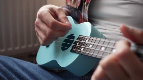 Person Playing Light Blue Ukulele Close Up