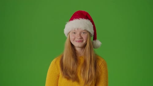 Écran vert Une adolescente radieuse se tient debout avec un sourire éclatant enfilant un chapeau de père Noël