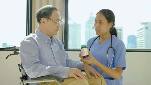Healthcare Worker Explains Pills to Patient in Wheelchair