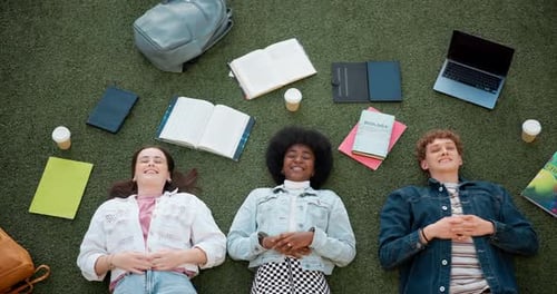 Students Relaxing on Ground with Books and Laptop