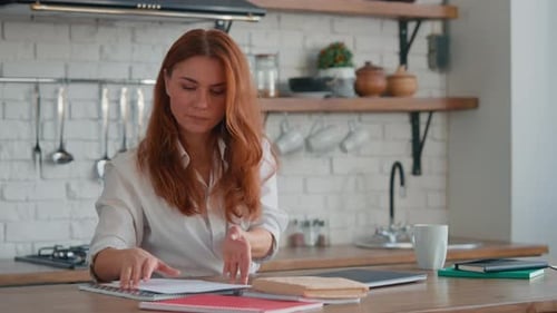 Woman Organizes Paperwork on Counter in Kitchen