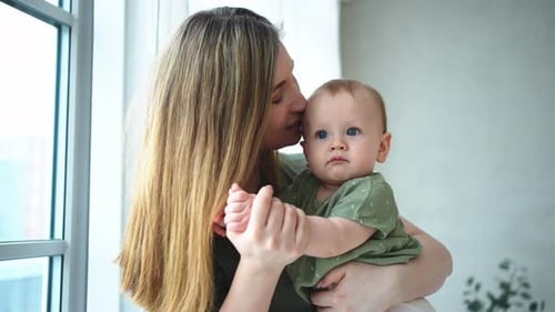 Mother Holding and Kissing Adorable Baby