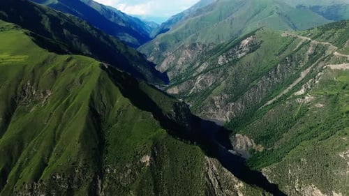 Sweeping Aerial View of Majestic Green Mountains and a Deep Gorge with a Meandering River