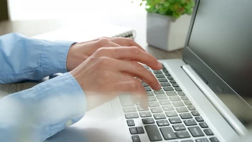 Close-up of a business woman's hands working on a laptop keyboard.