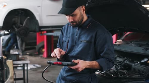 Digital tablet in hands. Mechanic working in a car service station.