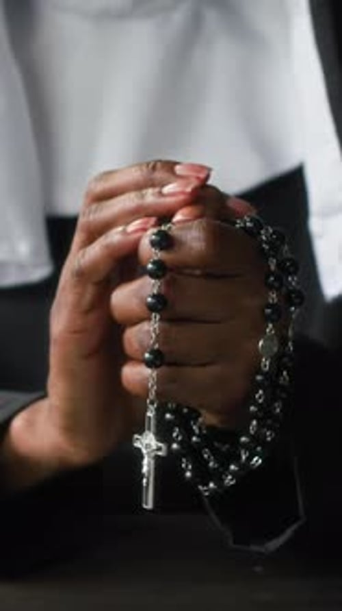 Close-up of Unrecognisable Nun Praying with Clasped Hands Holding Rosary