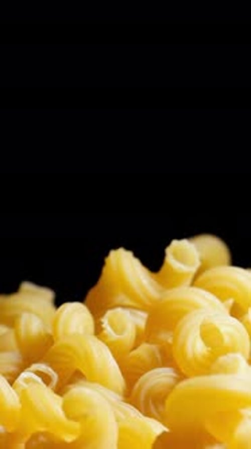 Raw macaroni pasta falls gracefully in stunning slow motion.