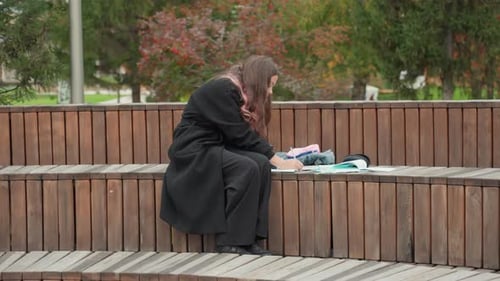 Teenage Girl Studying on Wooden Bench in Park