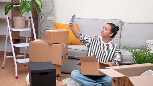 Woman Taking Selfie Surrounded by Moving Boxes