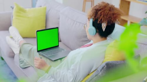 Black woman, sofa and headphones for dancing with laptop, green screen mockup