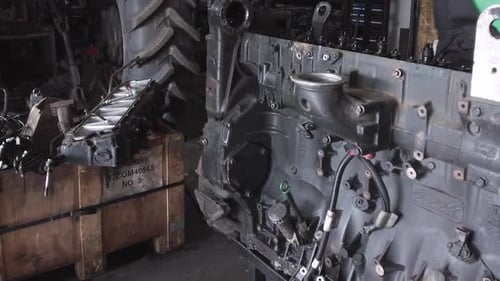 Mechanic Inspecting Tractor Engine Parts