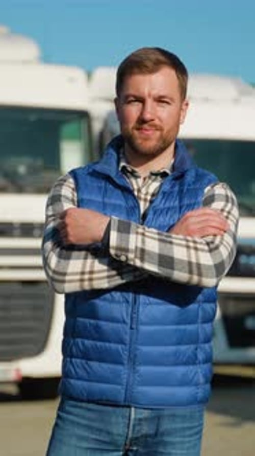 Truck Driver Standing Proudly in Front of Delivery Trucks