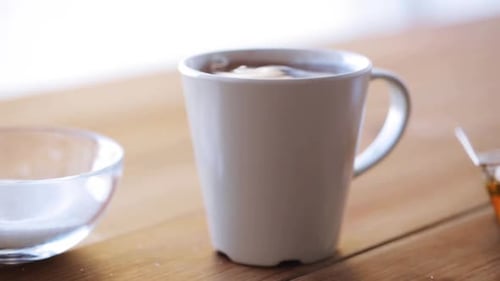 Unhealthy Eating and Drinks Concept - Hand with Teaspoon Adding Sugar To