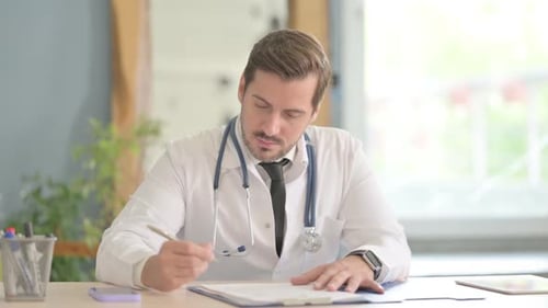Male Doctor Working on Medical Report in Clinic