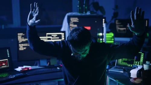 Person Raising Hands in a Dark Workspace