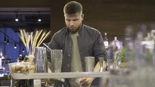 bearded bartender preparing a cocktail in a bar