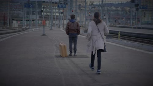 Réunion d'une mère célibataire et d'un fils adolescent s'embrassant sur un quai de chemin de fer
