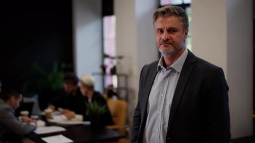 Confident Businessman in Office with Team Meeting