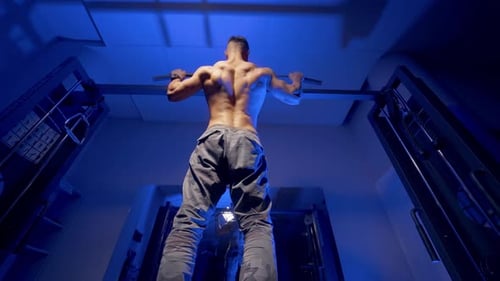 Mann macht Klimmzugtraining. Junger Mann macht drinnen Klimmzüge auf einer horizontalen Stange