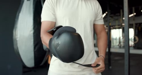Person Putting On Black Boxing Gloves in Gym