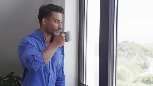 Man Drinks Coffee and Looks out the Window