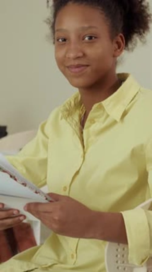 Teen Smiling While Reviewing Papers Indoors