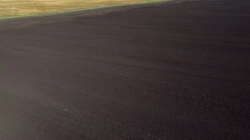 Flight Over a Plowed Field of Black Soil on a Sunny Day A Dug Up Field of Earth