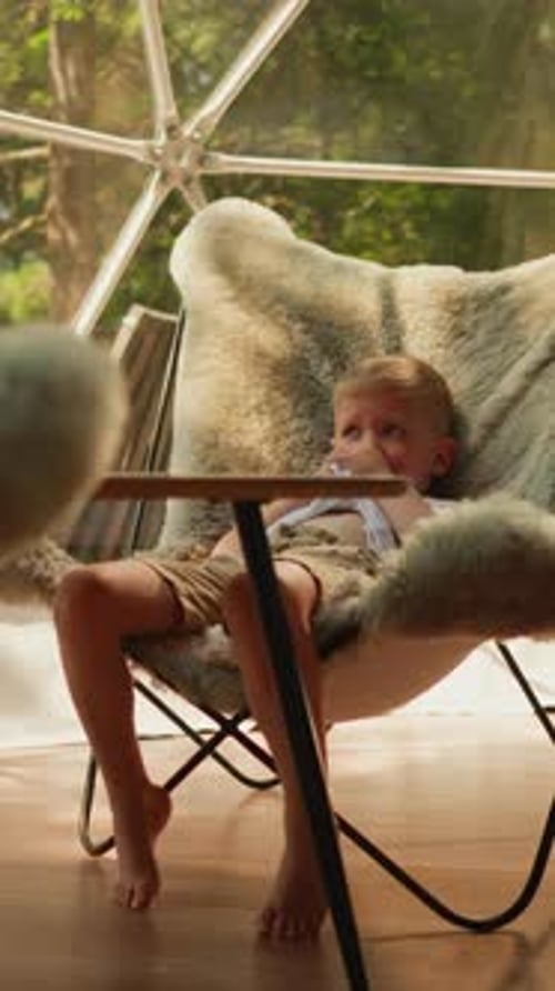Siblings Sit in Fur Armchairs in Glamping Camp Relaxing