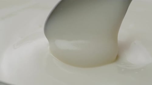 White Creamy Sauce Texture Closeup Dip a Spoon Into White Yogurt Macro Dairy Products Concept