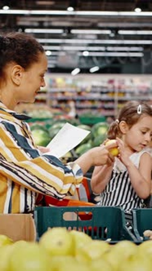 Lovely Family Mother and Little Daughter Buy Lemons in the Hypermarket in the Fruit Section Girl