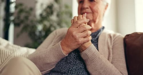 Senior Woman Sitting with Hands Clasped in Home