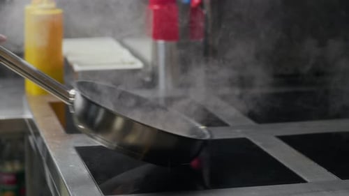 Hands of Chef Frying Ingredients on Pan at Restaurant Kitchen