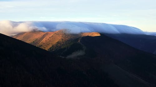 Las nubes se derraman sobre la cresta de la montaña Otoño en las montañas de un parque nacional de los Cárpatos