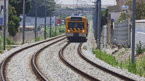 Train de banlieue jaune circulant sur des voies ferrées incurvées