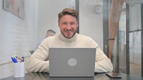 Man Smiling at Laptop in the Office