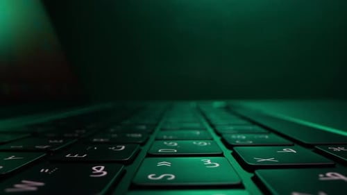 Laptop Keyboard Close-Up with Green Lighting in Dark Environment