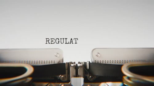 Old mechanical typewriter typing Regulatory Compliance in a close-up view.