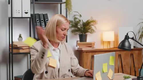 Exhausted Caucasian Mature Businesswoman with Sticky Notes and Laptop Sitting at Home Office Desk