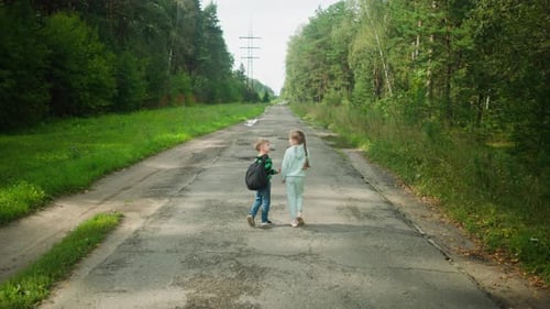 Boy Talking to Sister While Walking on Paved Road with Potholes