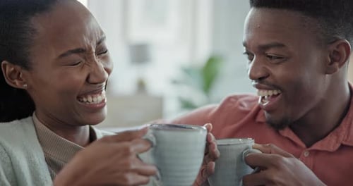 Young Couple Laughing and Drinking Coffee Indoors