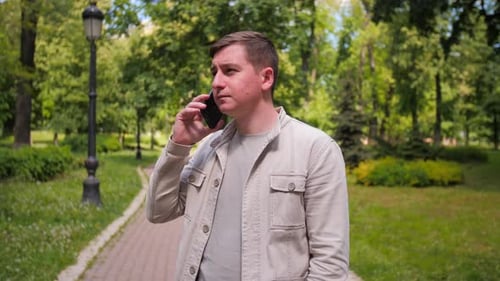 A Man is Talking on the Phone on the Street A Guy in a Jacket Makes a Call