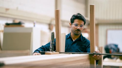 Professional Carpenter Assembling Wooden Furniture in a Workshop