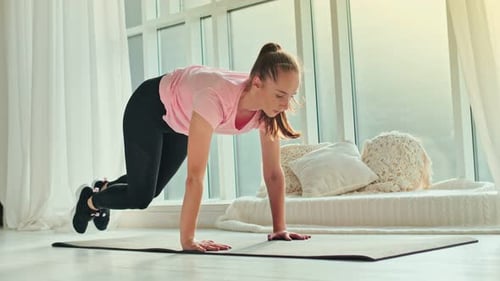 Young Woman Exercises in Brightly Lit Room