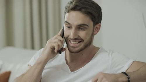 Smiling man talking on phone indoors at home