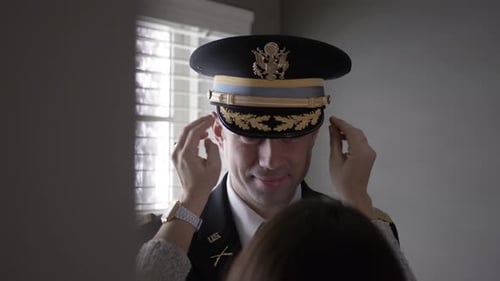 Wife Adjusts Husband's Military Uniform in Home