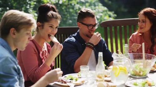 Happy friends enjoying summer garden party with food and drinks outdoors