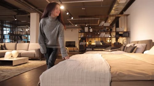 Young Woman Browsing Beds in Modern Furniture Store